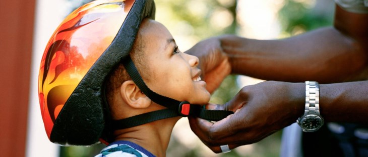 Ett barn får hjälp att knäppa cykelhjälmen.