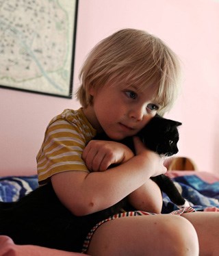 Barn som kramar en svar kattunge.