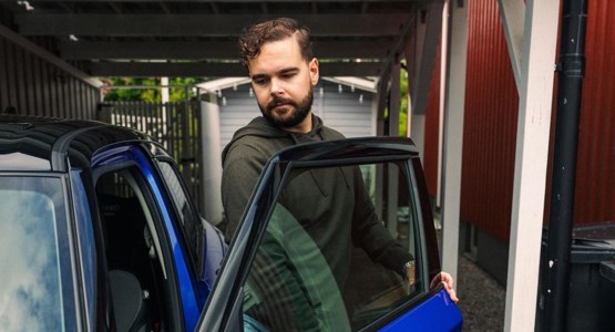 Man som öppnar dörren på en blå bil