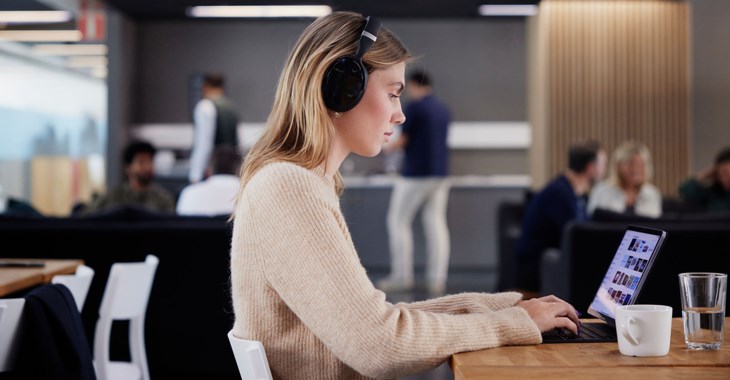 En kvinna sitter vid en bärbardator i kontorsmiljö.