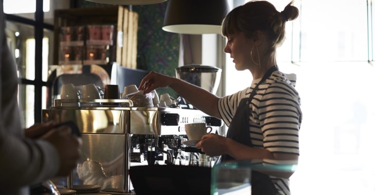 Person som jobbar på ett café och står och gör kaffe.