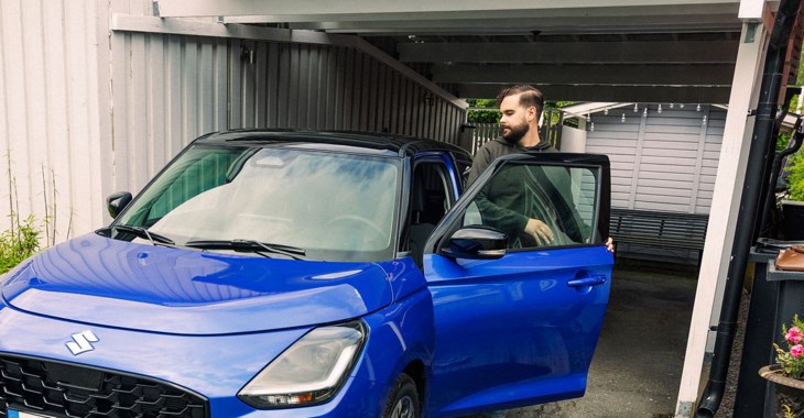 Man står i carport och kliver in i bil.