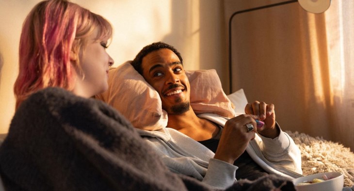 Ett ungt par sitter i soffan och pratar.