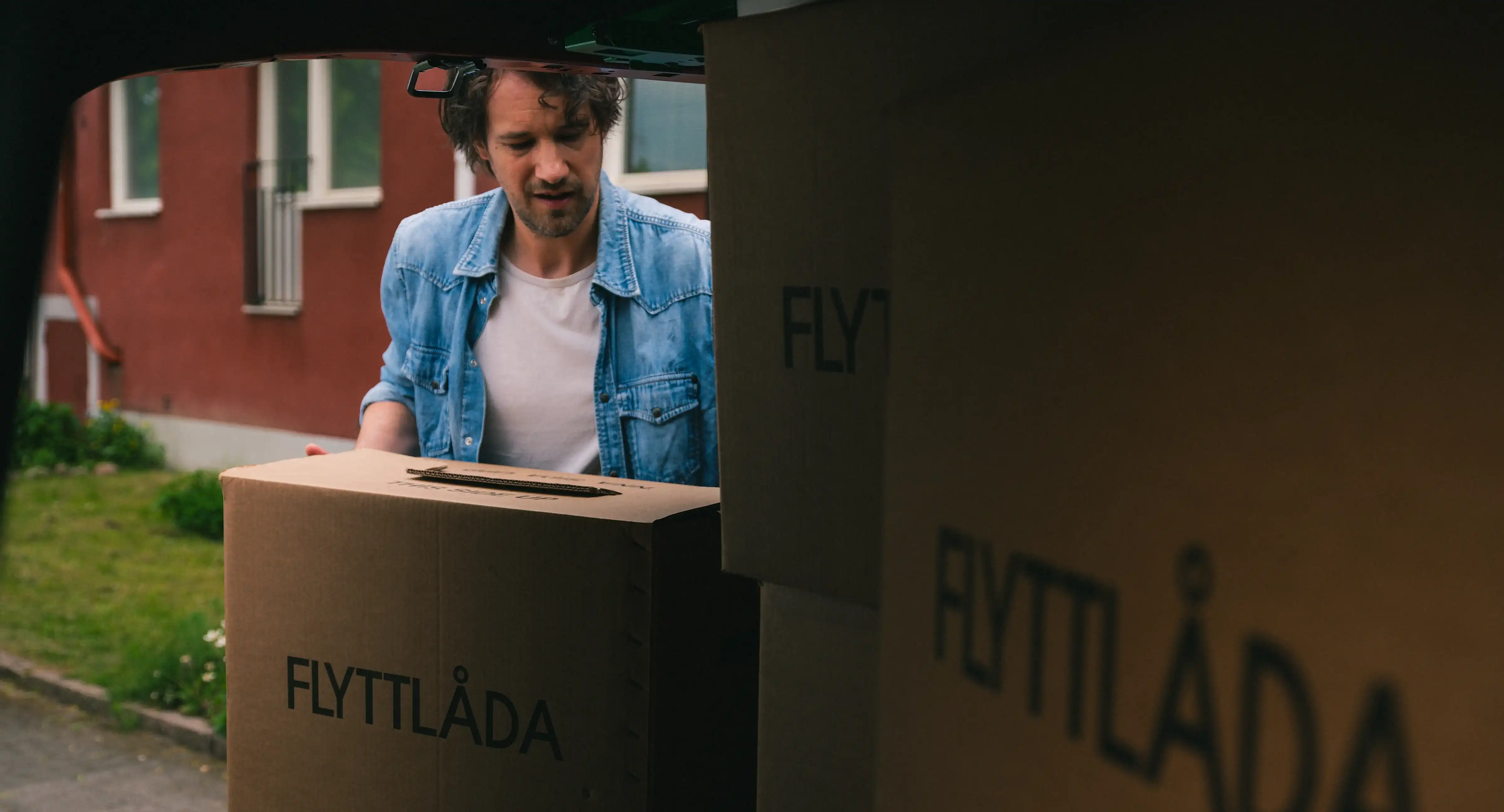 Man packar in flyttlådor i bilen.