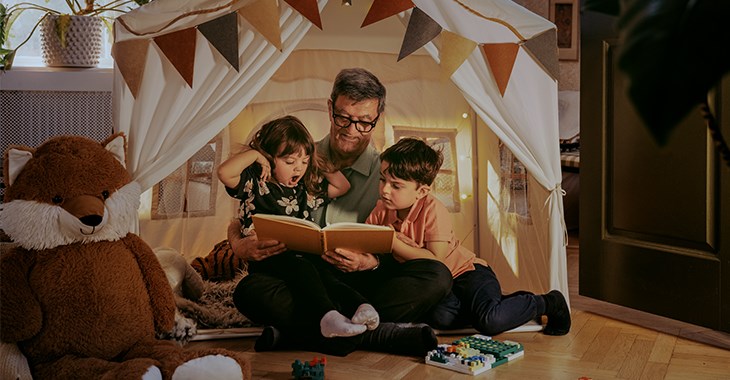 En morfar har samlat sina barnbarn i en koja för att läsa saga.