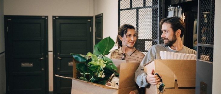 Par bär in flyttlådor i hiss.