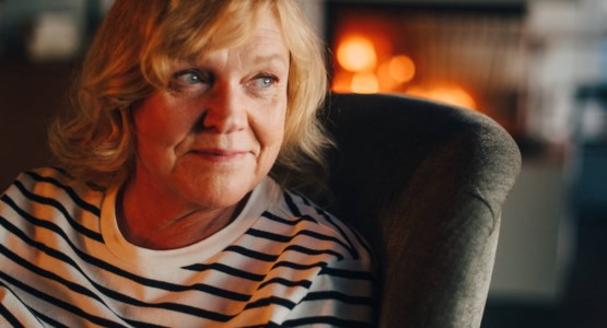 Kvinna sitter vid brasa.