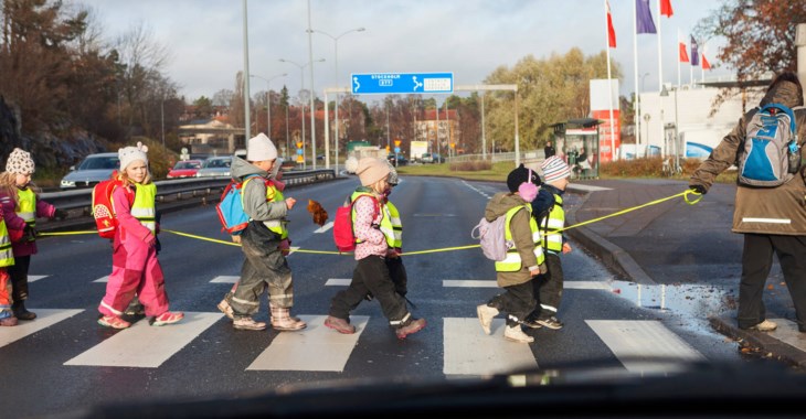 Barn leker ute i reflexvästar.