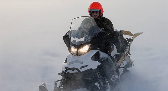 En person som sitter på sin snöskoter och är redo att köra iväg.