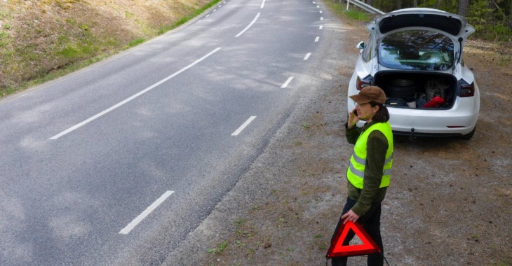 Man vid vägkant med varningstriangel.