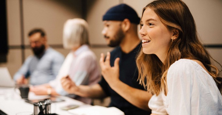 Unga företagare som sitter vi ett mötesbord och diskuterar glatt.