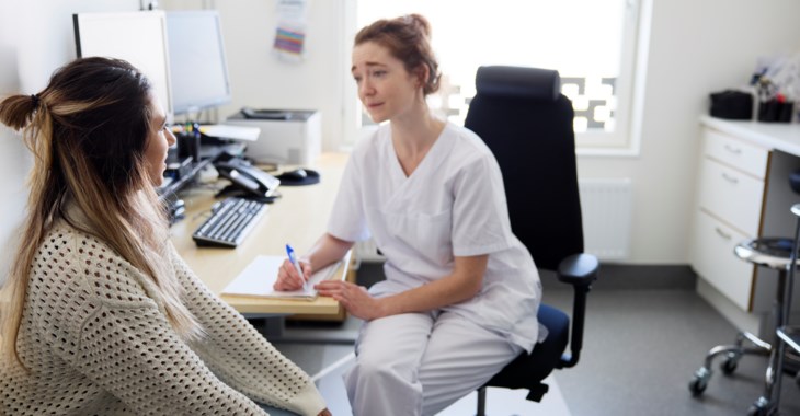 Kvinnlig läkare pratar med kvinnlig patient