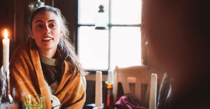 Tjej som sitter vid ett bord med levande ljus.