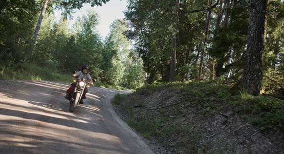 Man kör motorcykel på grusväg.