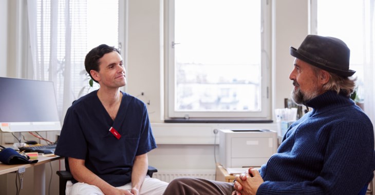 Manlig läkare pratar med manlig patient