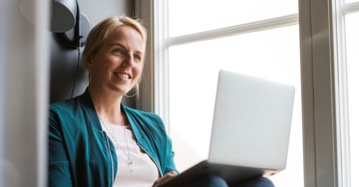 Kvinna sitter i fönster med dator.