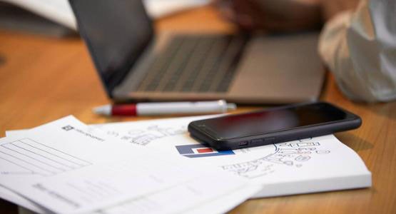 En dator och en mobil på ett skrivbord.