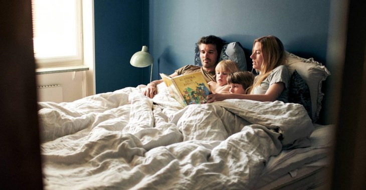 Foto på familj som läser godnattsaga i sängen.