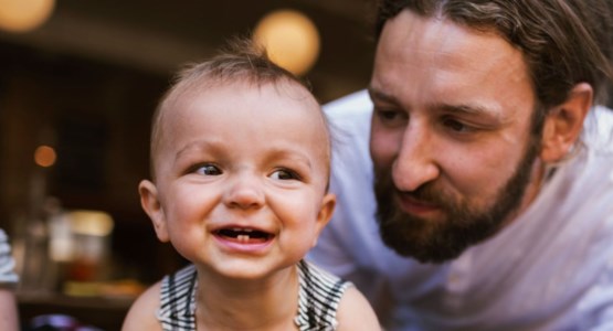 Krypande bebis busar med sin pappa.