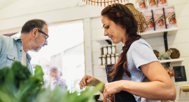 En kassörska på ett café hanterar en kunds beställning.