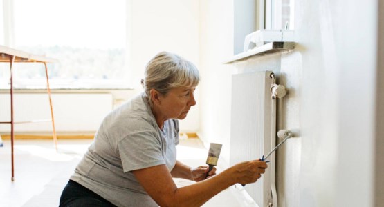 Kvinna sitter på golvet och målar vägg