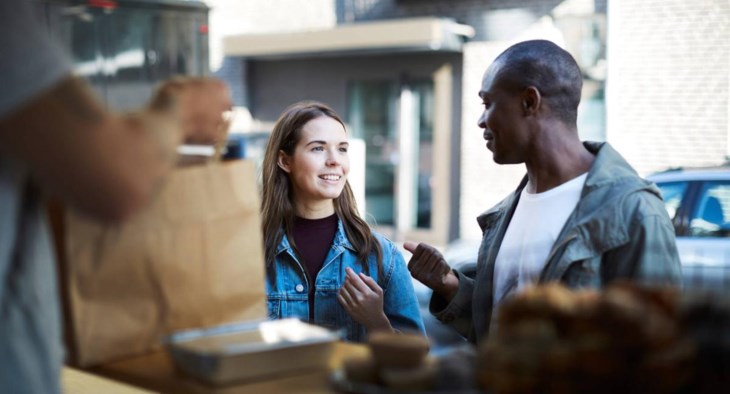 Två vänner står vid en foodtruck.