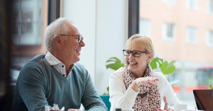 Äldre par samtalar och ler mot varandra.