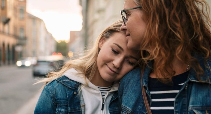 En mamma med sitt tonårsbarn kramas om på stan.