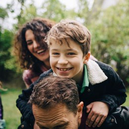 Skrattande pojke sitter på sin pappas axlar.