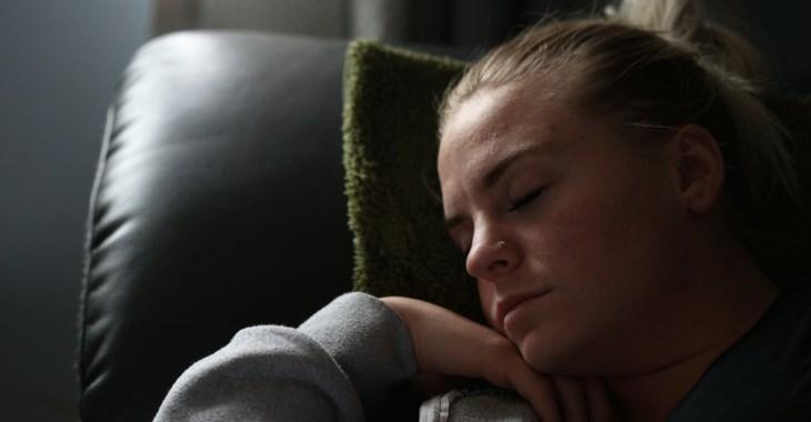 En tjej som vilar på en kudde i soffan.