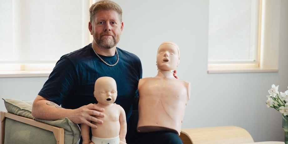 Man med två HLR dockor i knät