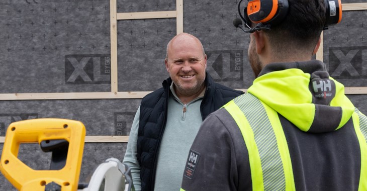 Företagaren Fredrik Bladås står  och prtare med en arbetare i gul varseljacka