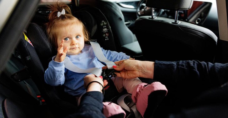 Liten tjej i bakåtvänd bilbarnstol.