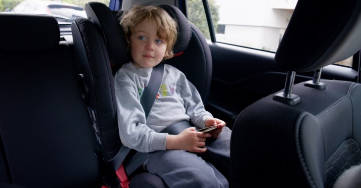 Barn som sitter i bältesstol i bil.