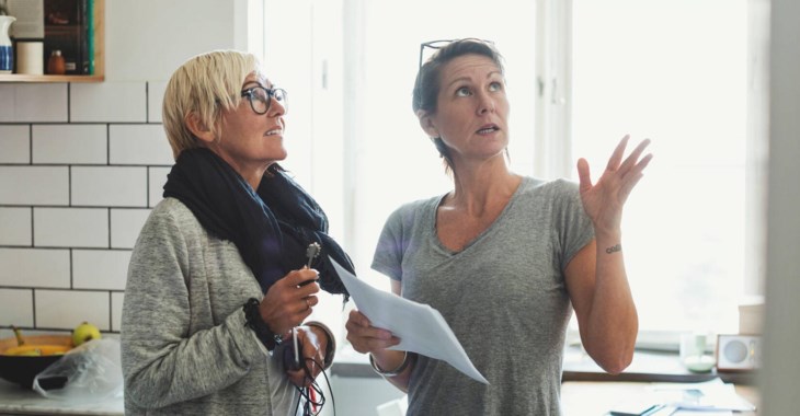 Två kvinnor står i ett kök och samtalar.