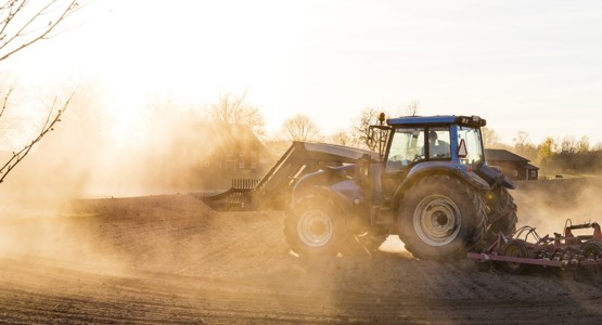 Traktor på åker, fotografi.