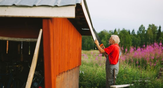 Äldre man sågar på tak