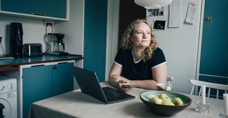 Kvinna sitter i köket och tittar ut genom fönstret.