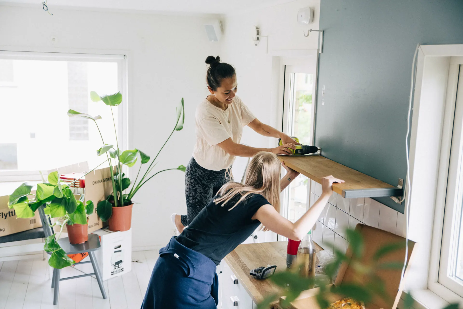 Två tjejer sätter upp en hylla.