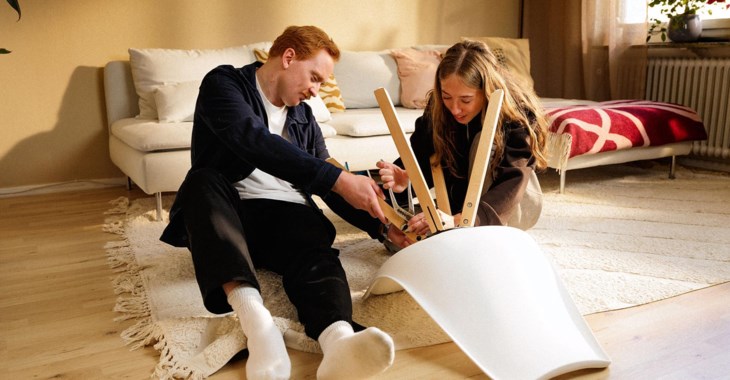 Två sambos skruvar ihop en stol tillsammans.