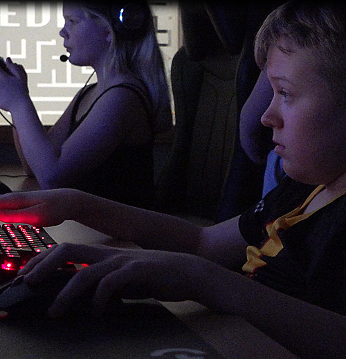 Pojke och flicka sitter bredvid varandra och spelar datorspel.