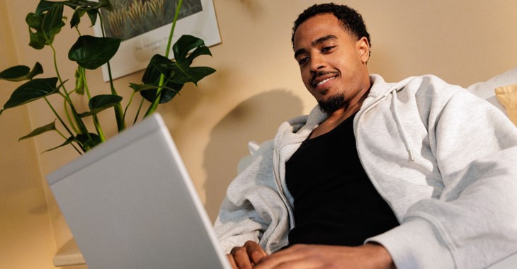 En ung man sitter vid sin laptop och sätter upp en budget.