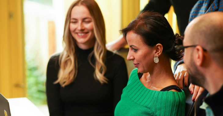 Två kvinnor och en man jobbar vid en dator.