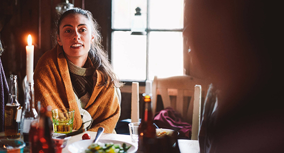 Kvinna samtal med en vän över en middag med tända ljus.