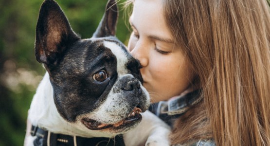 Ung flicka med hund i famnen.