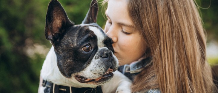 Flicka håller hund i famnen.