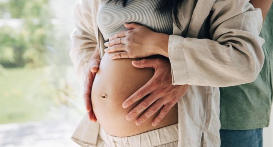 par som håller händer på en gravidmage.