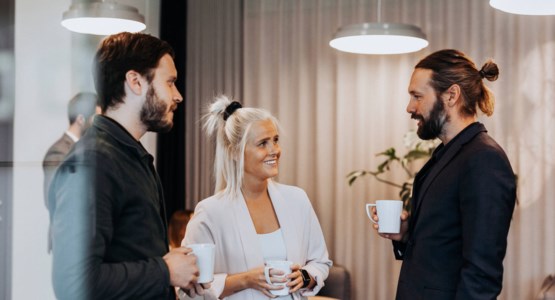 Tre kollegor står och pratar på ett kontor