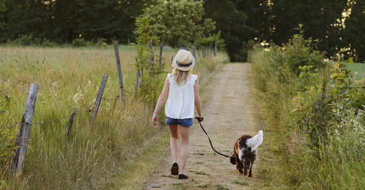 flicka promenerar på landsväg med en hund