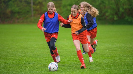 Tre tjejer spelar fotboll